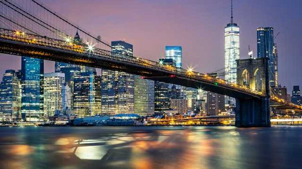 A night time view of the Brooklyn Bridge with the city in the background