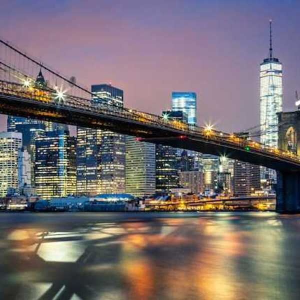 A night time view of the Brooklyn Bridge with the city in the background