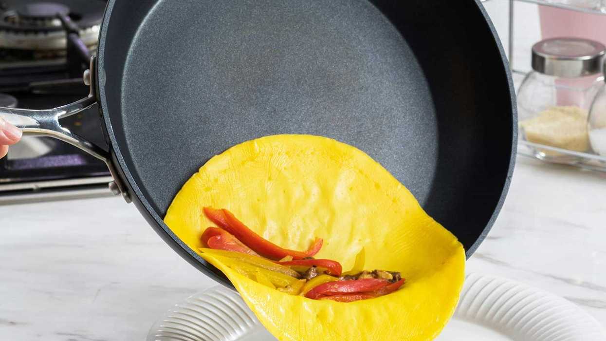 a nonstick frying pan with an omelette and red peppers inside of it.