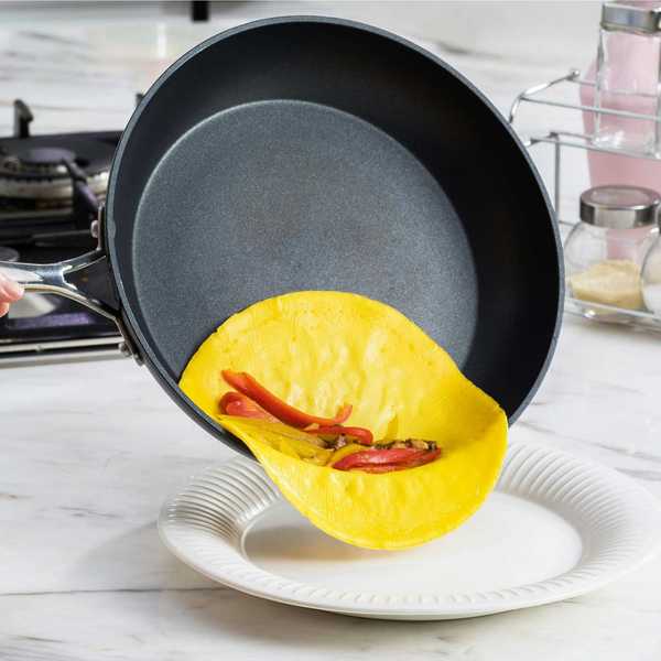 a nonstick frying pan with an omelette and red peppers inside of it.
