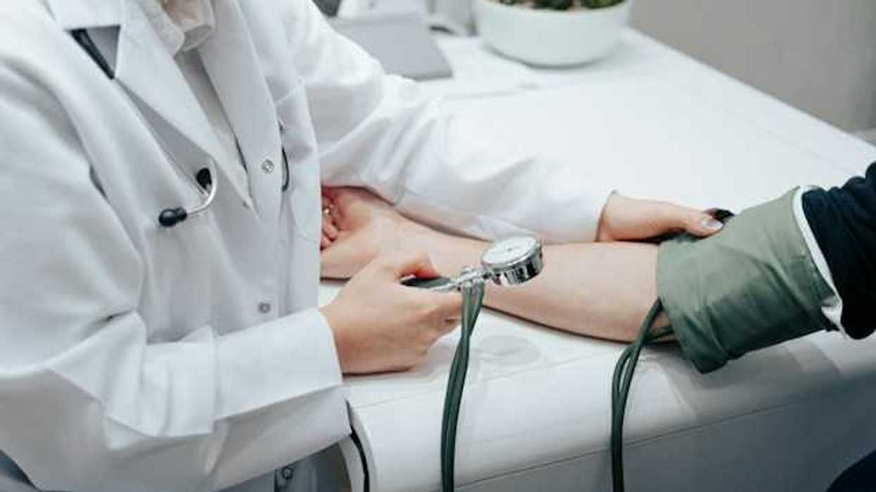 A nurse holding a blood pressure gauge while taking a patient's blood pressure