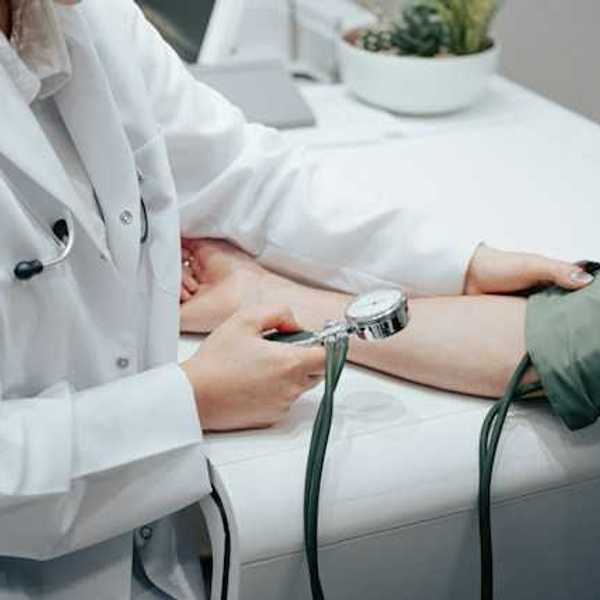 A nurse holding a blood pressure gauge while taking a patient's blood pressure