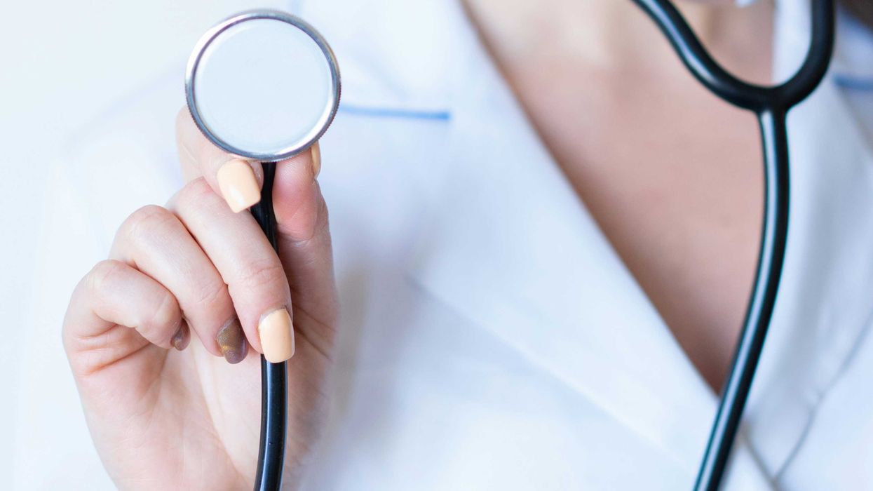 a nurse in a white coat holding a stethoscope.