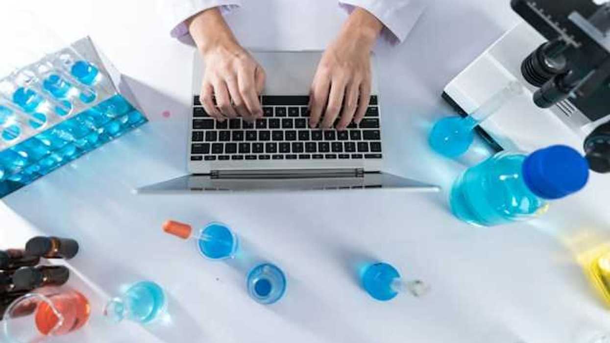 A overhead view of a scientist at a desk typing on a laptop