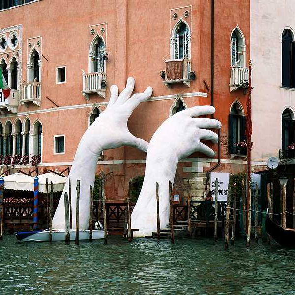 A pair of giant hands rising out of a Venice canal to hold up a building