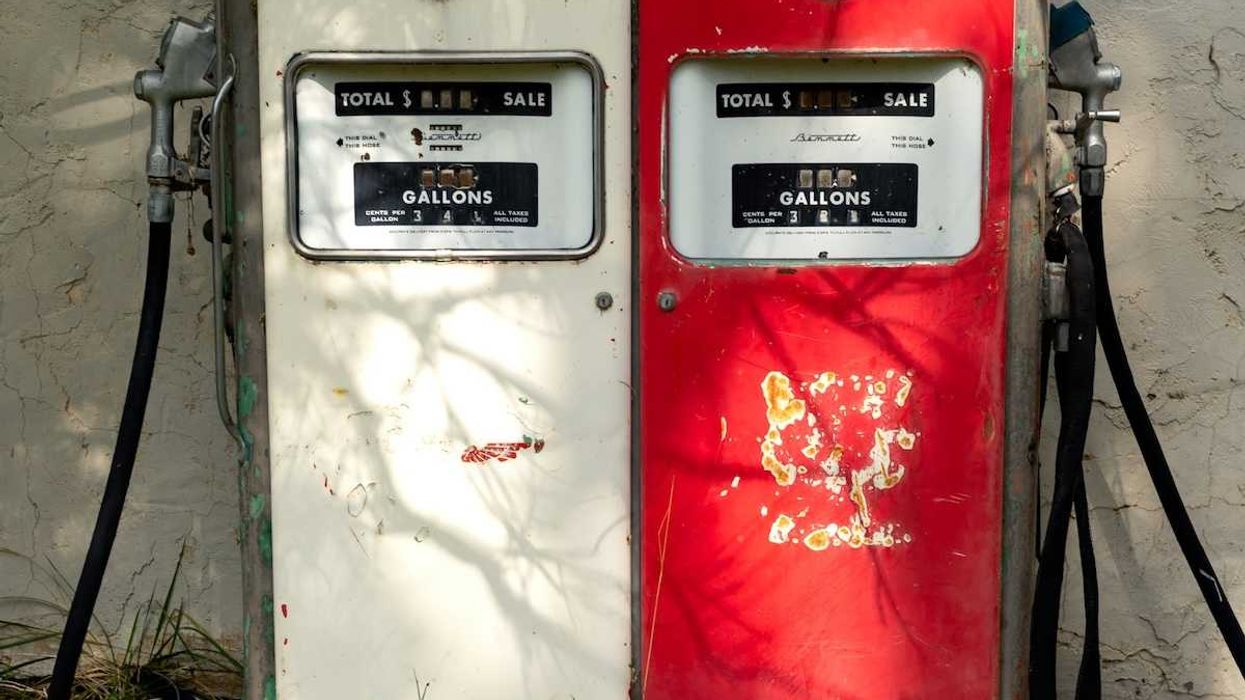 A pair of old gas pumps—one white, one red—juxtaposed side-by-side