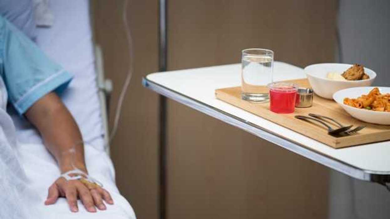 A patient sitting in a hospital bed next to a table with a meal