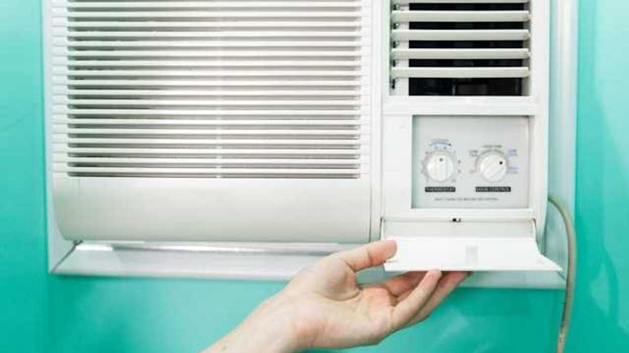 A person adjusting the temperature on a wall air conditioning unit
