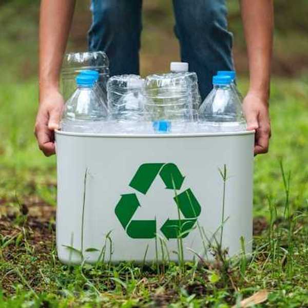 A person collecting plastic bottles in a recycling container