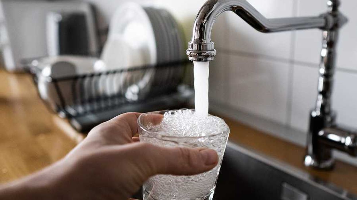 A person filling a glass of water at the kitchen sink