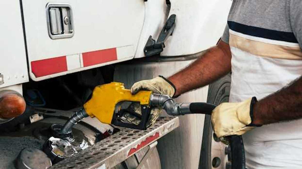A person fueling a large truck with a yellow nozzle