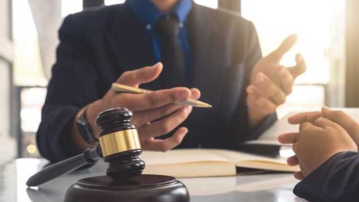 A person gesturing at another person with a court gavel in front of them