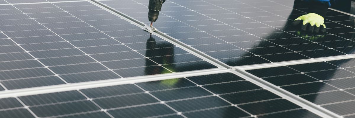 a person holding a a drill installing a solar panel.