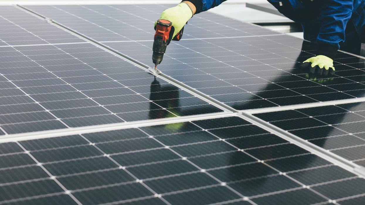 a person holding a a drill installing a solar panel.