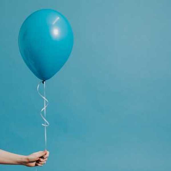 A person holding a blue balloon against a blue background