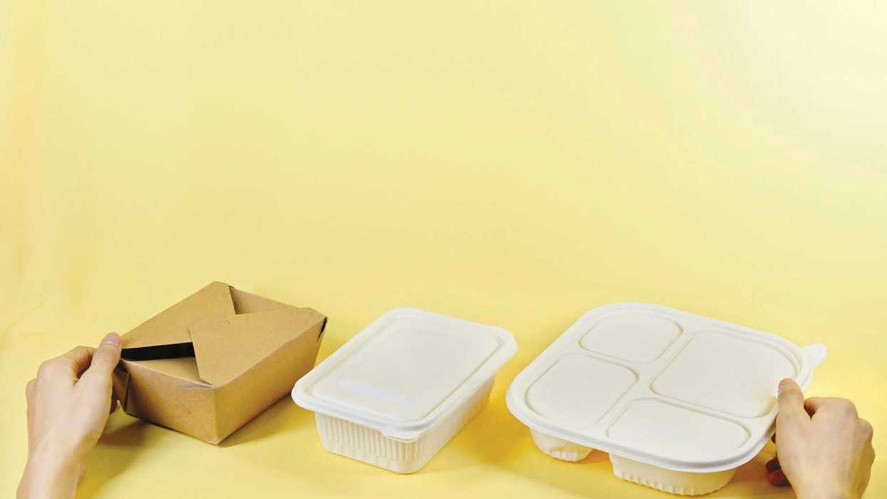 a person holding a box and two plastic take out containers.