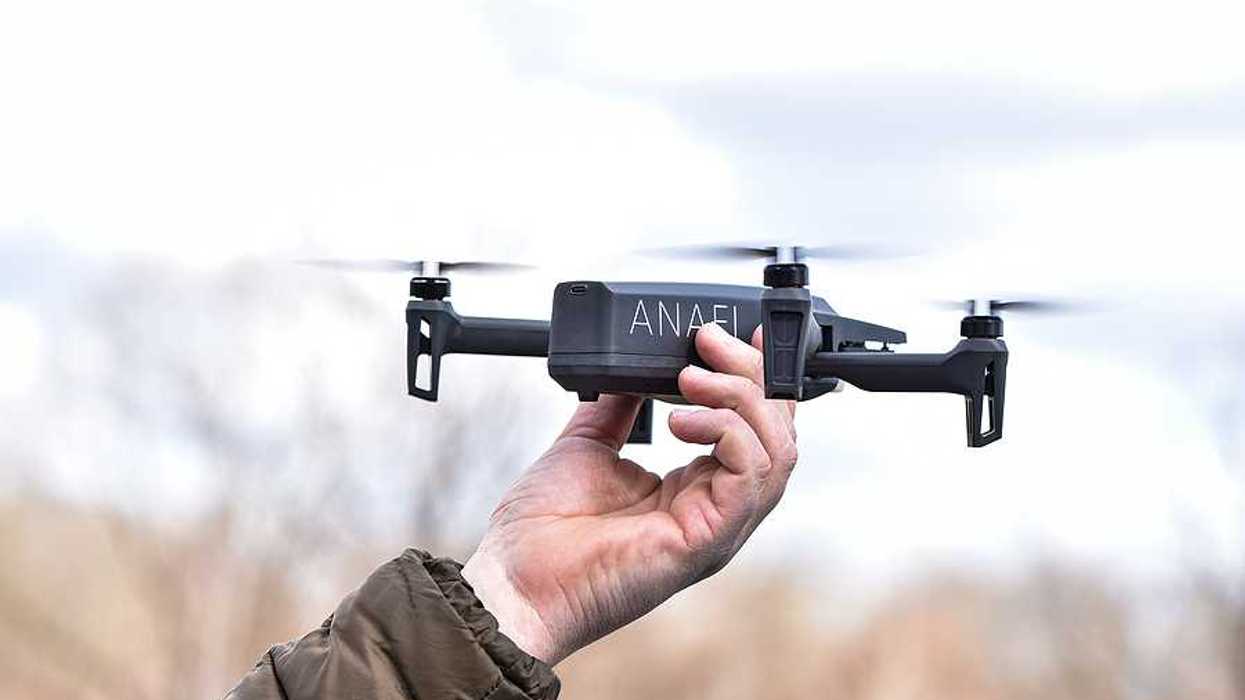 A person holding a drone aloft