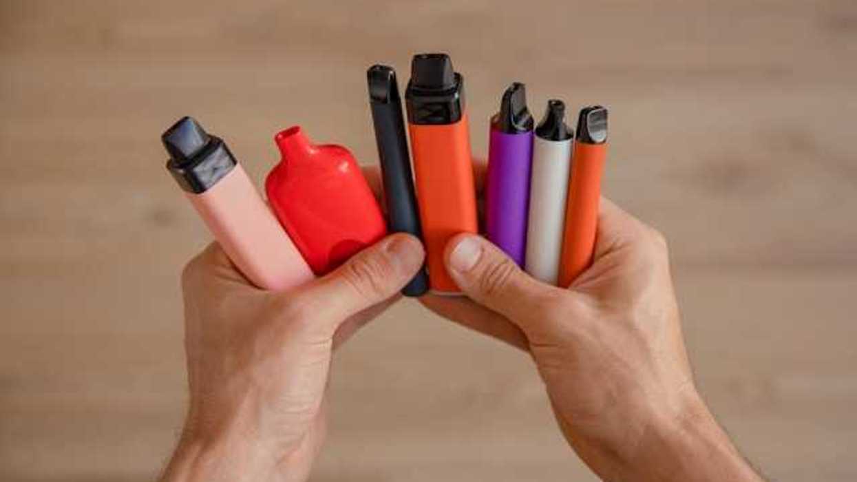 A person holding a group of multicolored vapes