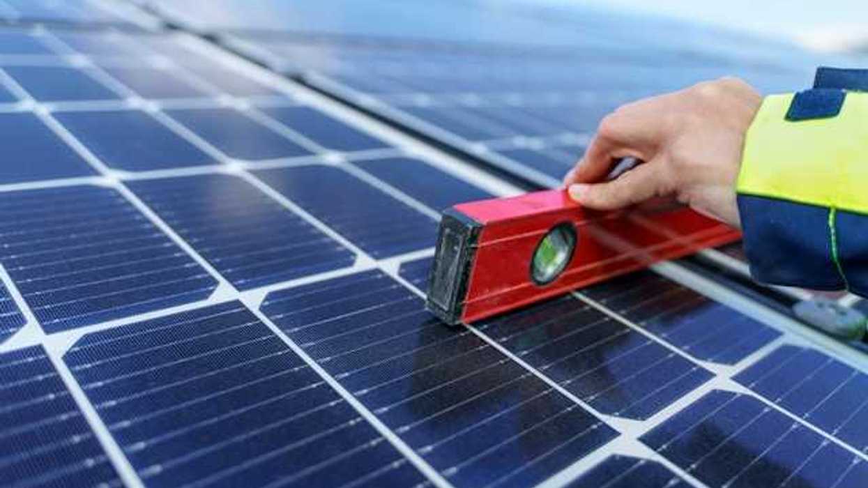 A person holding a level on a solar panel