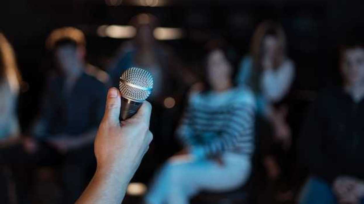 A person holding a microphone with people sitting in the background