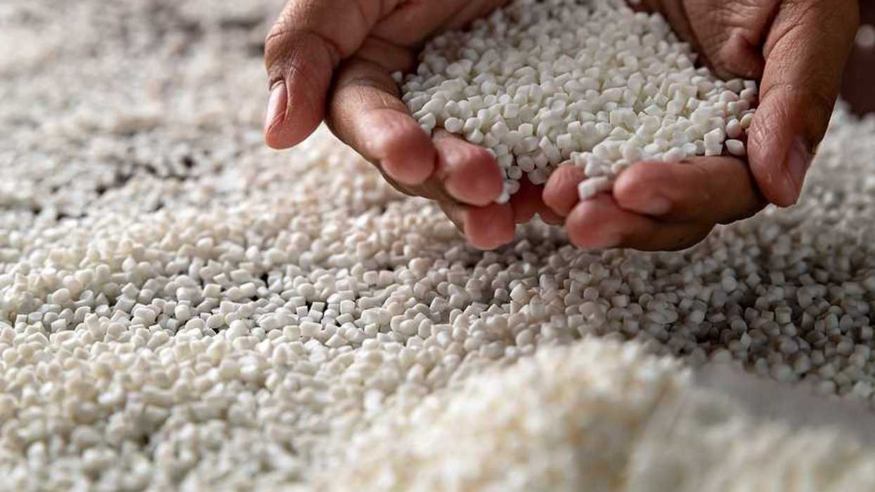 A person holding a pile of small white plastic pellets