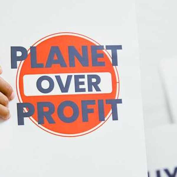 A person holding a sign that says Planet Over Profit