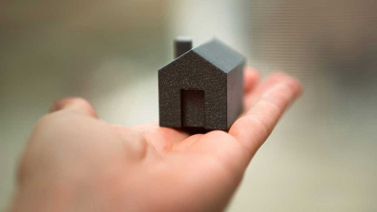 A person holding a small model of a house in their hand