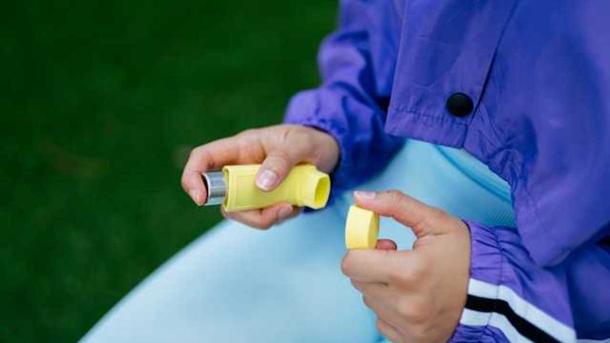A person holding a yellow inhaler