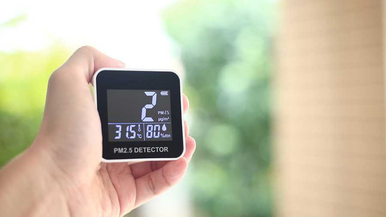 A person holding an air quality monitor display