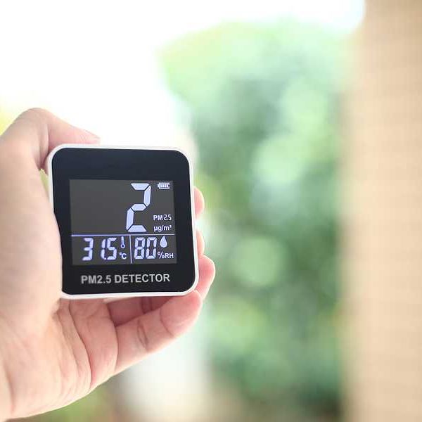 A person holding an air quality monitor display
