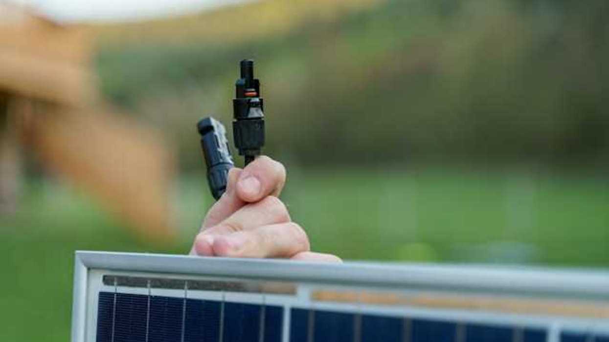 A person holding on to a small solar panel with plugs in their hand