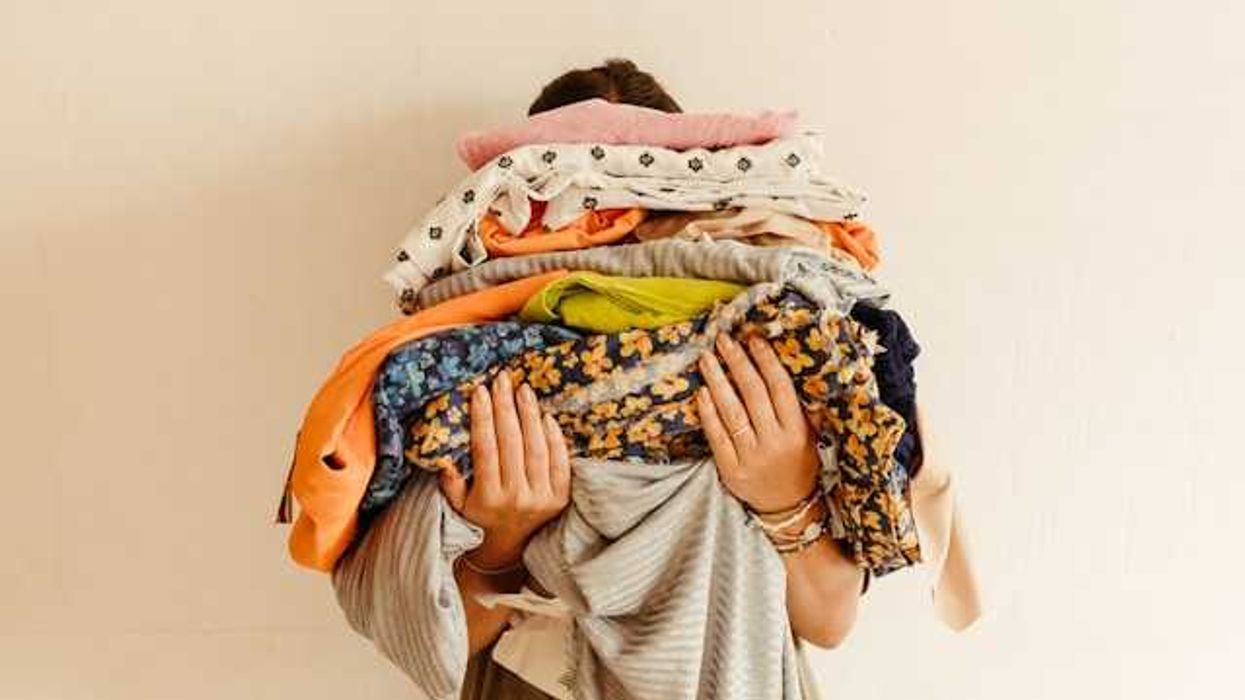 A person holding piles of multicolored fabric