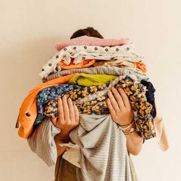 A person holding piles of multicolored fabric
