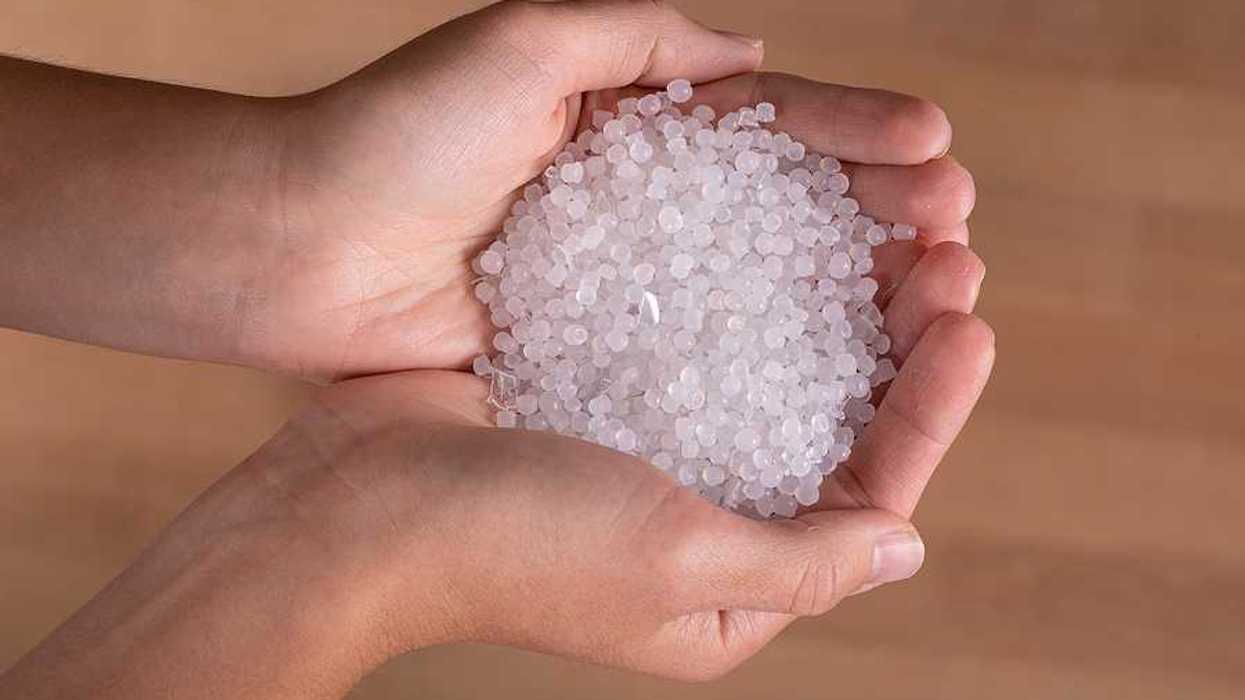 A person holding small plastic pellets in their hands