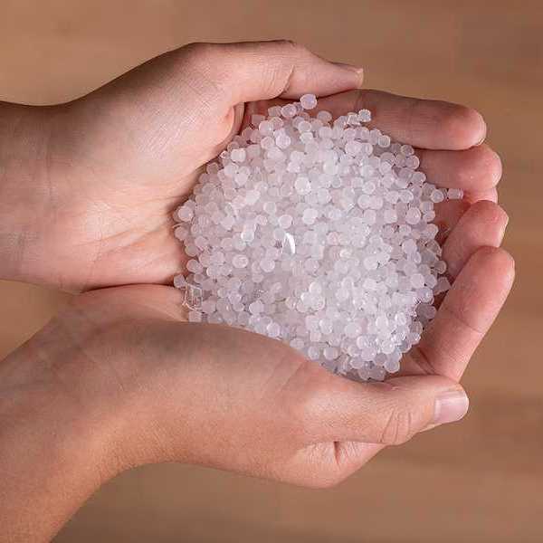 A person holding small plastic pellets in their hands