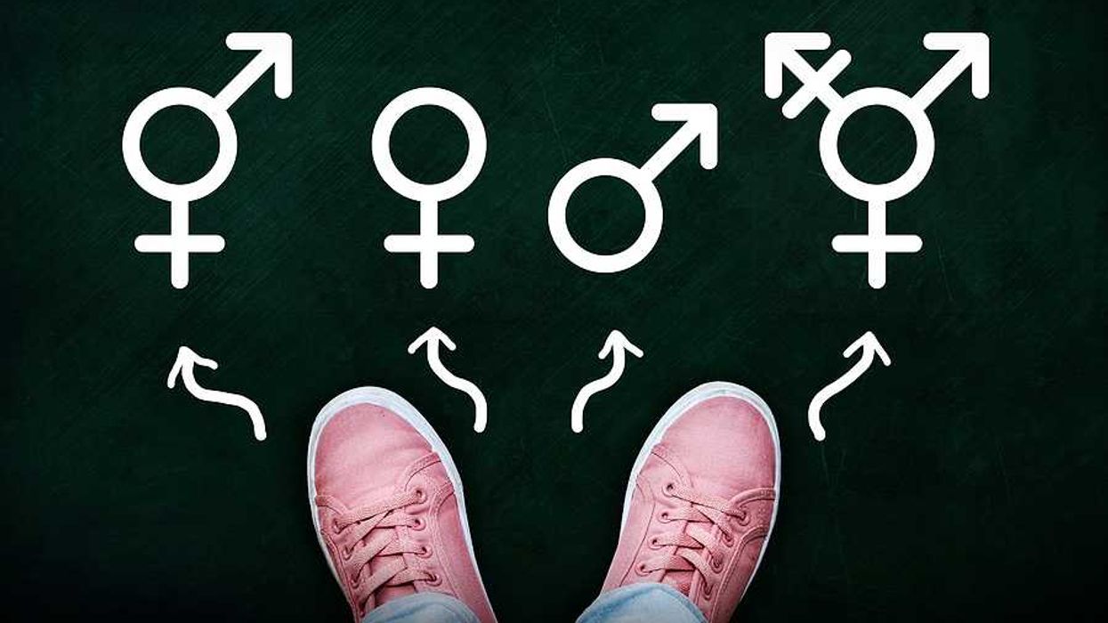 A person in pink tennis shoes looking at symbols of male, female, trans and bigender