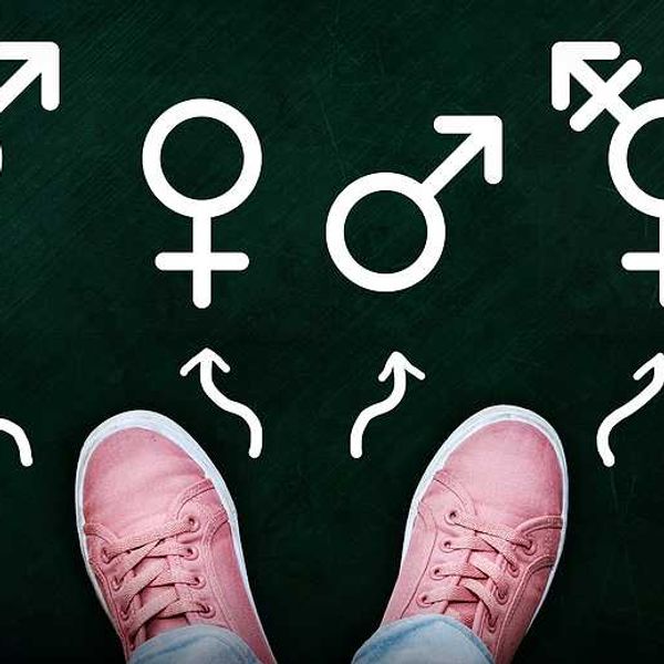 A person in pink tennis shoes looking at symbols of male, female, trans and bigender