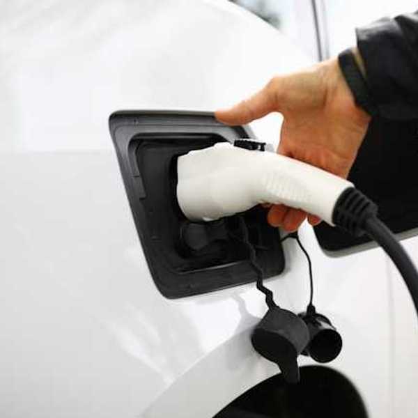 A person inserting a charger into an electric vehicle