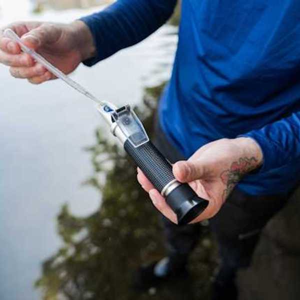 A person inserting a water sample into a testing tool
