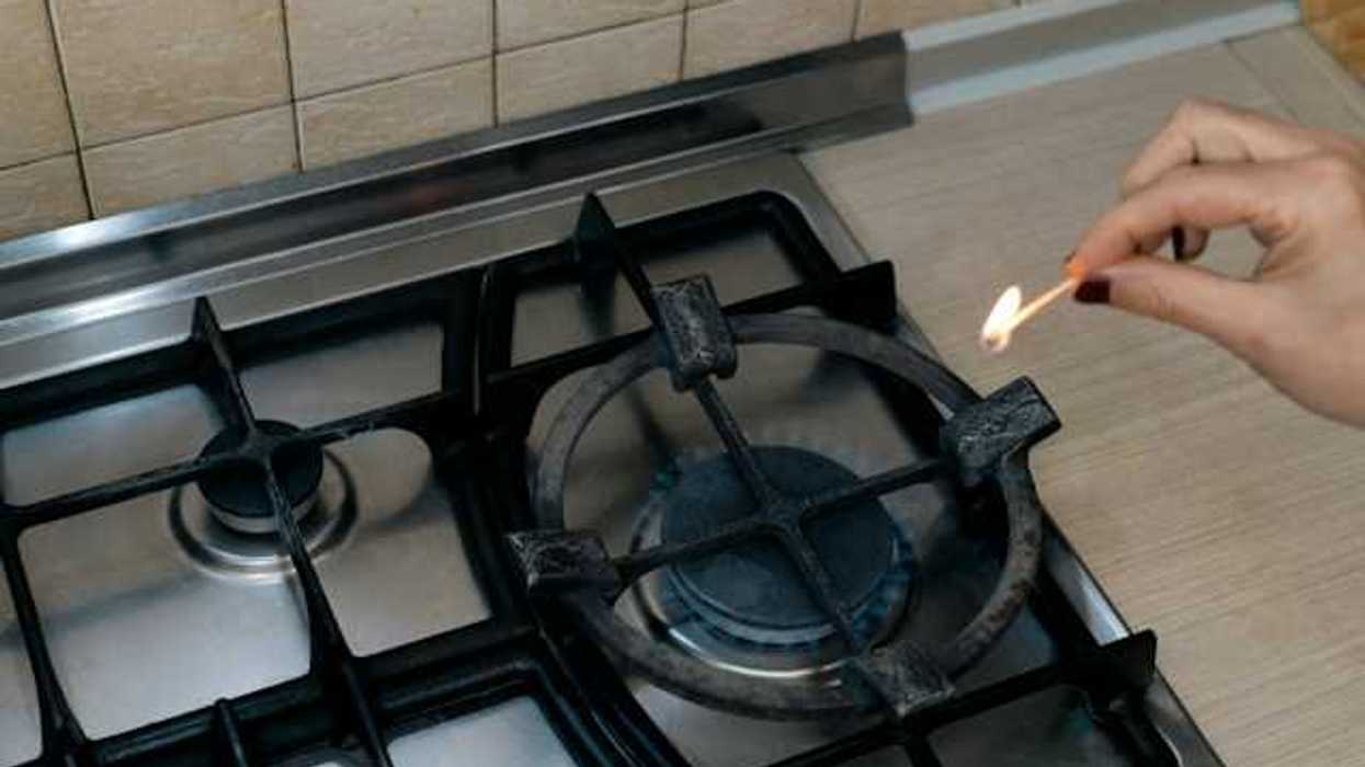 A person lighting a match on a gas stove