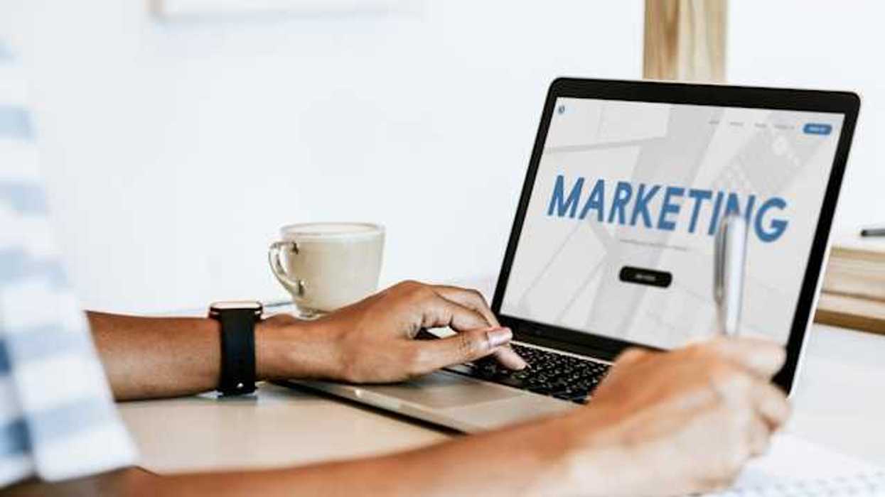 A person looking at a laptop with the word Marketing on the screen