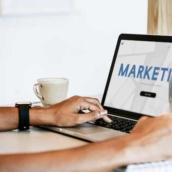A person looking at a laptop with the word Marketing on the screen