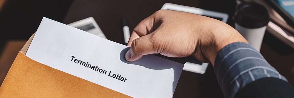 A person opening an envelope with a termination letter in it.