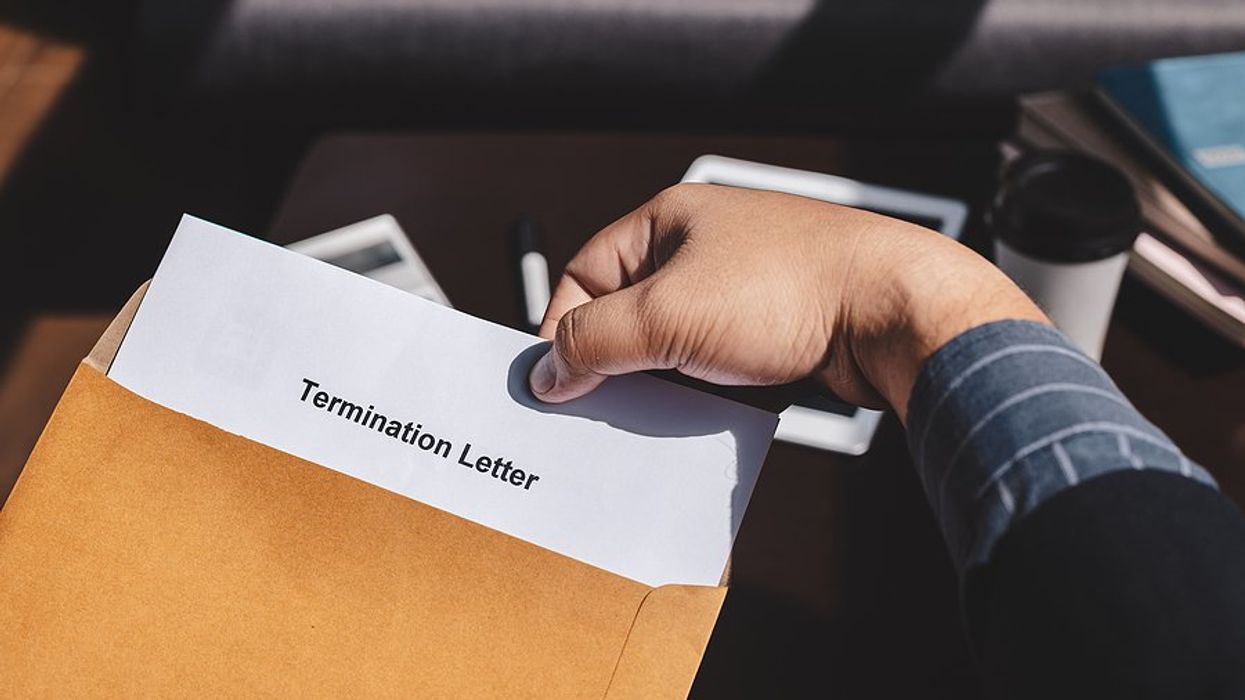 A person opening an envelope with a termination letter in it.
