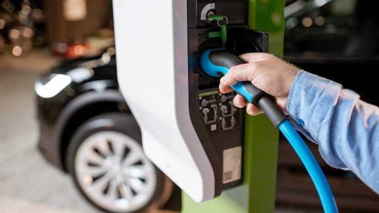 A person plugging an EV into a car charger