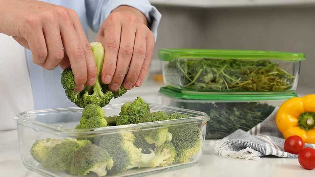 A person putting broccoli into a glass container