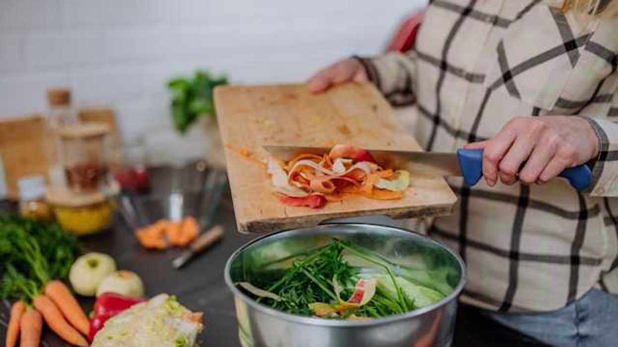 A person putting food into a composting container while cooking