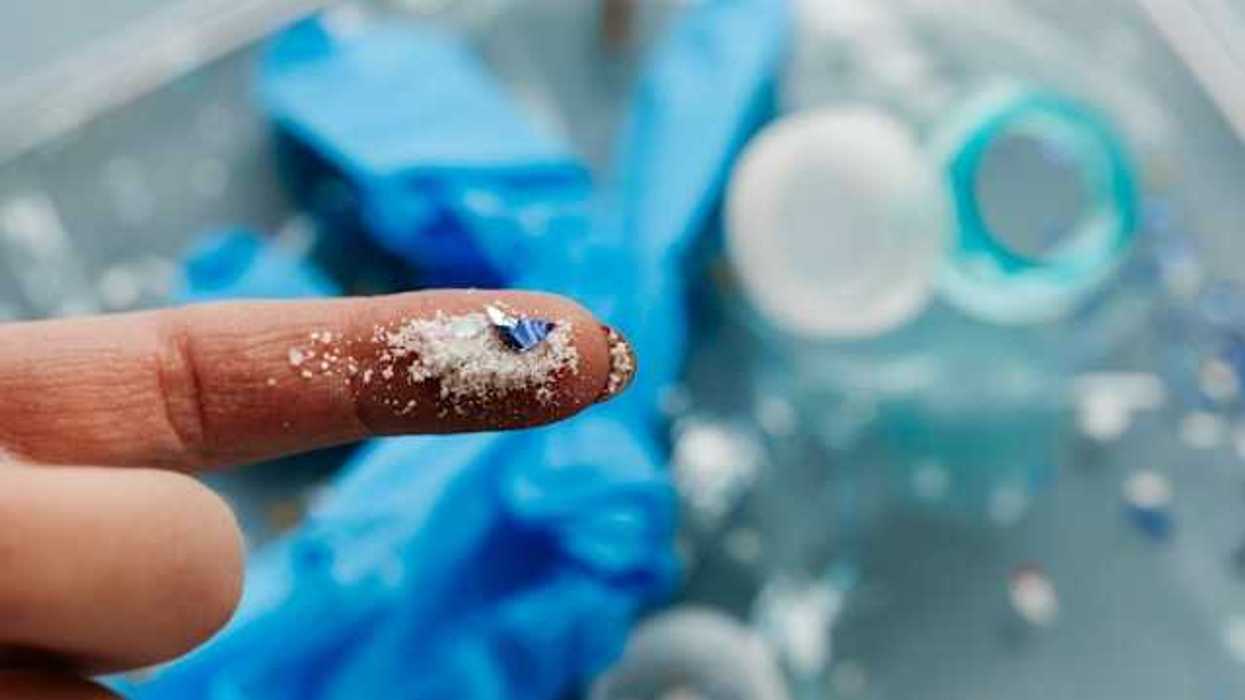 A person's finger holding small plastic particles