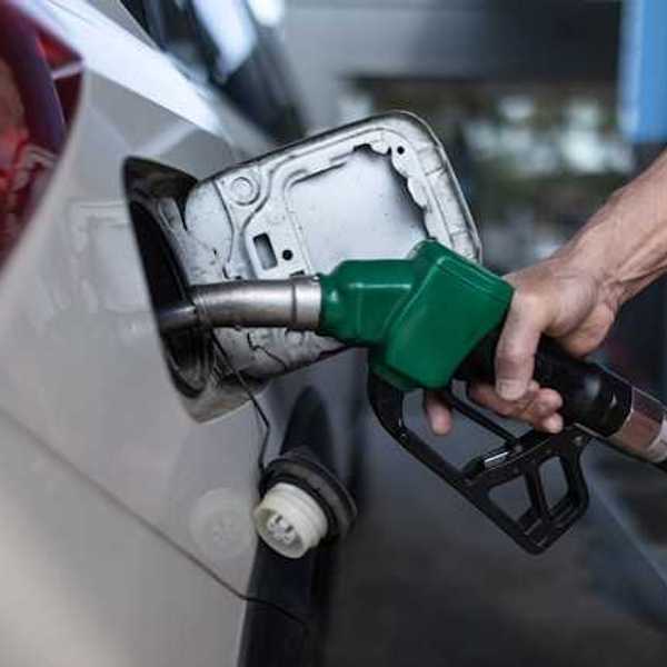 A person's hand holding a gas pump while pumping gas into car