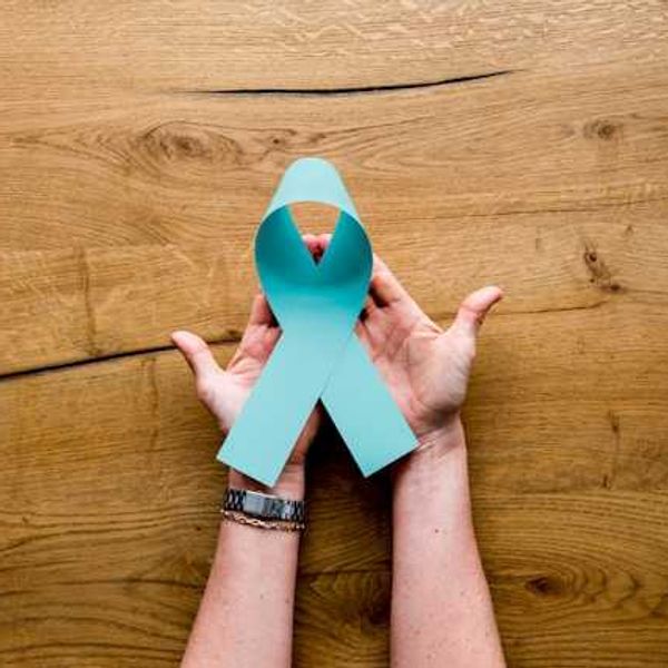 A person's hands holding a light blue ribbon